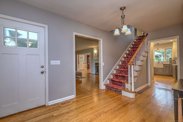691 Buttonball Rd, Orange, CT 06477 - foyer featuring stairway, light wood-type flooring, baseboards, and a chandelier