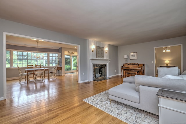 691 Buttonball Rd, Orange, CT 06477 - living room featuring light wood-style flooring, baseboards, a fireplace, and a chandelier