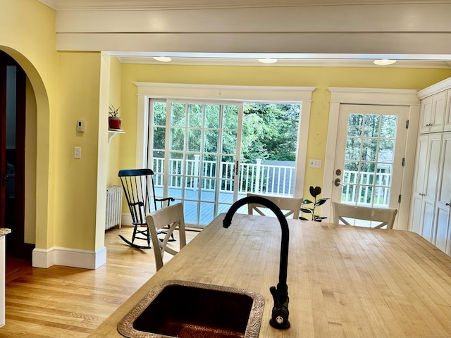 1666 Ridge Rd, North Haven, CT 06473 - kitchen with radiator, arched walkways, light wood-style flooring, crown molding, and white cabinetry