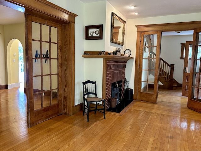 1666 Ridge Rd, North Haven, CT 06473 - living area with a brick fireplace, light wood-style flooring, arched walkways, and stairs