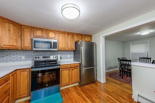 92 Blakeslee Ave, North Haven, CT 06473 - kitchen featuring stainless steel appliances, a baseboard radiator, backsplash, light wood finished floors, and brown cabinets