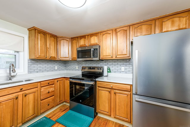 92 Blakeslee Ave, North Haven, CT 06473 - kitchen with appliances with stainless steel finishes, a sink, light wood-style floors, tasteful backsplash, and light countertops