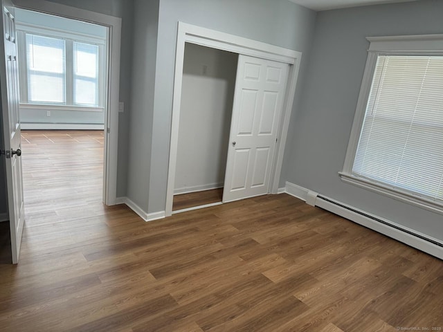 187 Jewett Ave, Bridgeport, CT 06606 - unfurnished bedroom with a baseboard radiator, wood finished floors, baseboards, a closet, and a baseboard heating unit