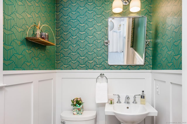 10 Fairfield Ave, Darien, CT 06820 - bathroom featuring a sink, toilet, wallpapered walls, a decorative wall, and wainscoting