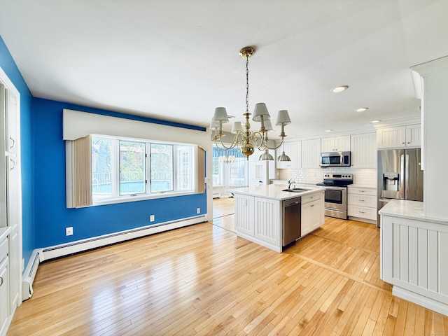 12 Rolling Ln, Norwalk, CT 06851 - kitchen featuring appliances with stainless steel finishes, a baseboard radiator, a chandelier, white cabinets, and light wood finished floors