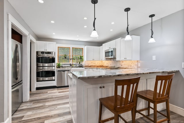 254 Haley Rd, Groton, CT 06355 - kitchen with stainless steel appliances, a peninsula, light wood-type flooring, recessed lighting, and light stone countertops