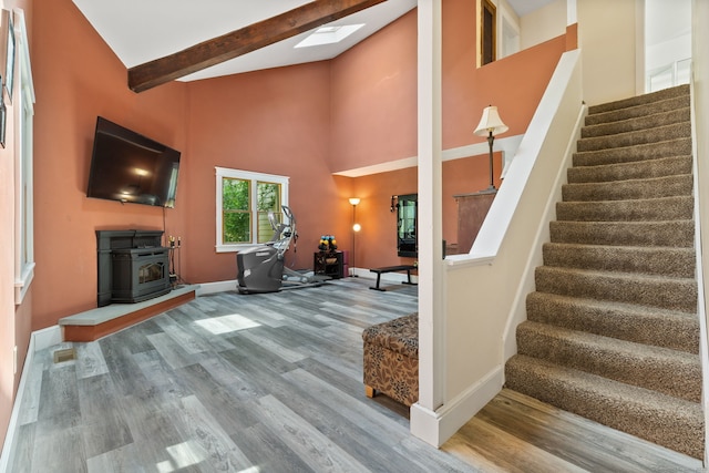 254 Haley Rd, Groton, CT 06355 - living area with stairs, wood finished floors, a wood stove, high vaulted ceiling, and a skylight