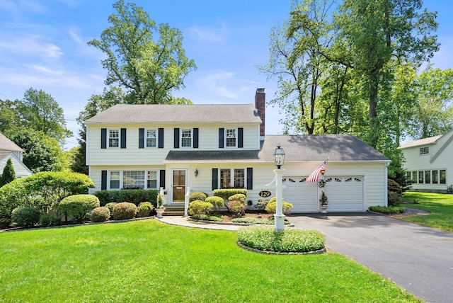 129 Brookmere Dr, Fairfield, CT 06824 - view of front facade with a chimney, a garage, driveway, and a front lawn