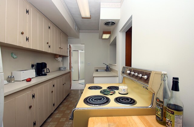 171 Main St, East Lyme, CT 06357 - kitchen featuring electric range oven, light countertops, a sink, white cabinets, and tile patterned floors