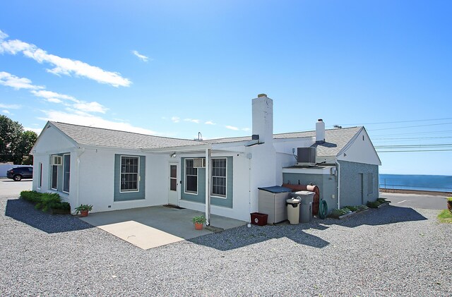 171 Main St, East Lyme, CT 06357 - back of property with a patio, stucco siding, a chimney, and a water view
