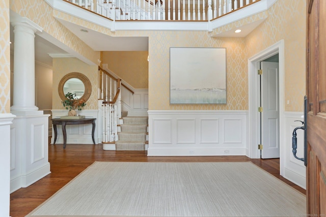 13 Witch Ln, Norwalk, CT 06853 - foyer with wood finished floors, ornate columns, stairs, a wainscoted wall, and a high ceiling