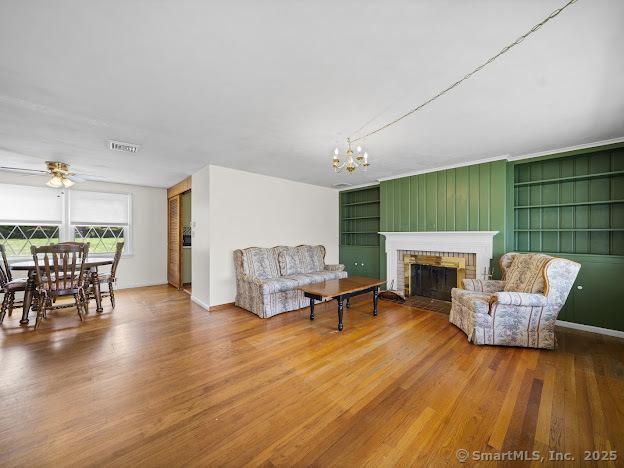 21 Poplar St, Enfield, CT 06082 - living area with wood finished floors, a fireplace, built in shelves, and a chandelier