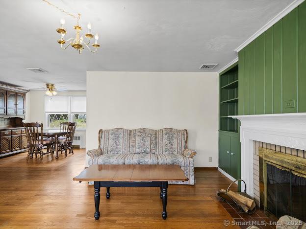 21 Poplar St, Enfield, CT 06082 - living room featuring wood finished floors, built in features, a chandelier, a fireplace, and ceiling fan