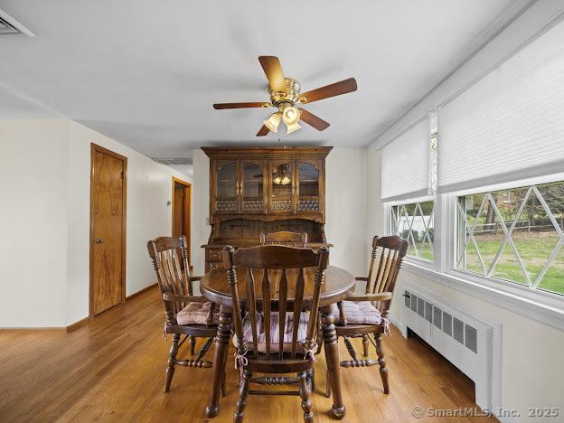21 Poplar St, Enfield, CT 06082 - dining area with radiator heating unit, ceiling fan, and light wood-type flooring