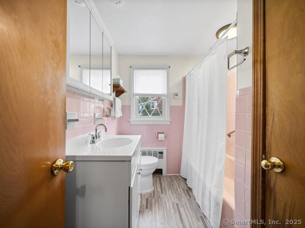 21 Poplar St, Enfield, CT 06082 - full bath featuring tile walls, vanity, toilet, radiator, and shower / bathtub combination with curtain