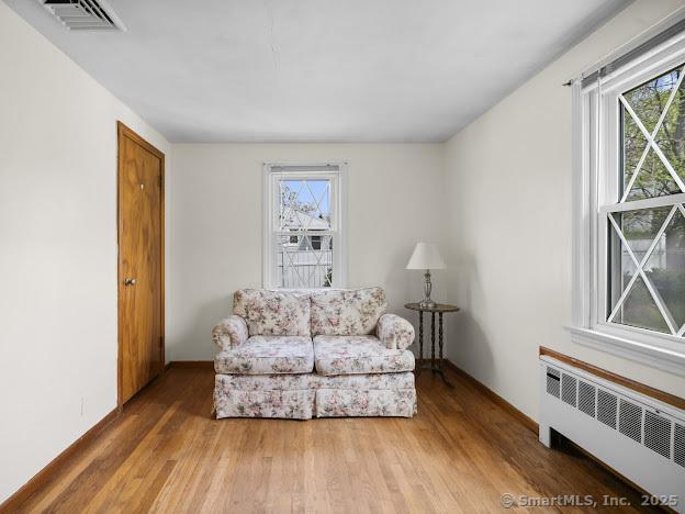 21 Poplar St, Enfield, CT 06082 - sitting room featuring radiator heating unit, healthy amount of natural light, and wood finished floors