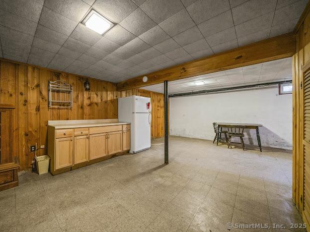 21 Poplar St, Enfield, CT 06082 - basement with freestanding refrigerator, wooden walls, and light floors