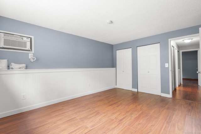 500 Darling St Unit 12M, Southington, CT 06489 - unfurnished bedroom with multiple closets, wood finished floors, wainscoting, baseboards, and an AC wall unit
