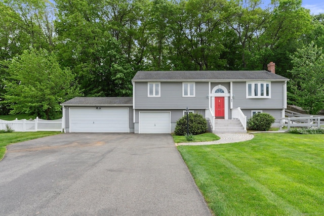 43 Worthington Rd, Glastonbury, CT 06033 - raised ranch featuring asphalt driveway, a chimney, view of wooded area, and a garage
