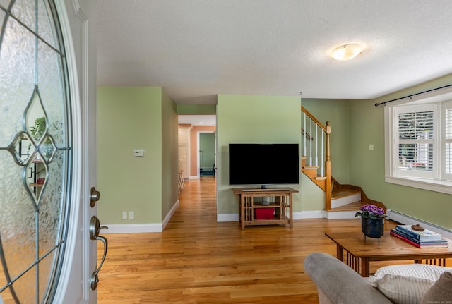 113 E Rd, East Windsor, CT 06016 - living room featuring a textured ceiling, stairway, light wood-type flooring, baseboards, and baseboard heating