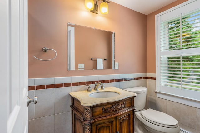 113 E Rd, East Windsor, CT 06016 - half bathroom featuring tile walls, toilet, vanity, healthy amount of natural light, and a wainscoted wall