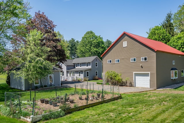 113 E Rd, East Windsor, CT 06016 - rear view of house featuring a vegetable garden, a lawn, driveway, and an attached garage