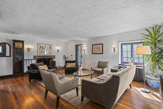 128 Blake Rd, Hamden, CT 06517 - living room with dark wood finished floors, a textured ceiling, a brick fireplace, and radiator heating unit