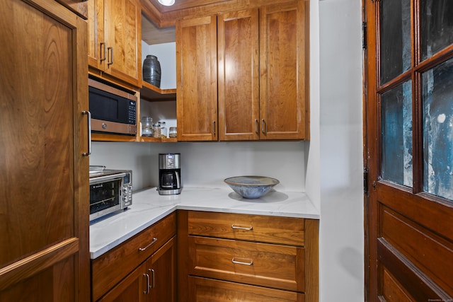 128 Blake Rd, Hamden, CT 06517 - kitchen with stainless steel microwave, brown cabinets, light stone countertops, and open shelves