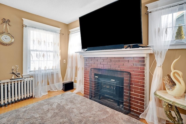 809 Burnside Ave, East Hartford, CT 06108 - detailed view of radiator, a brick fireplace, wood finished floors, and baseboards