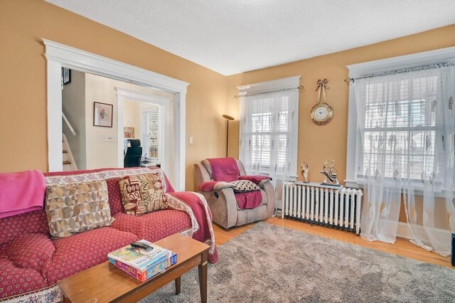 809 Burnside Ave, East Hartford, CT 06108 - living room featuring radiator, wood finished floors, and stairs