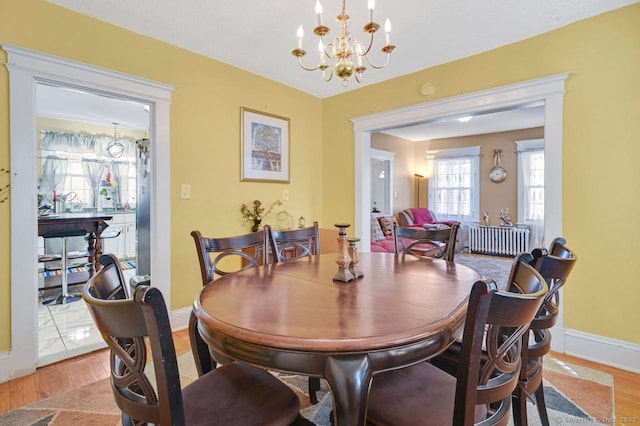 809 Burnside Ave, East Hartford, CT 06108 - dining room featuring radiator heating unit, light wood-style floors, baseboards, and a chandelier