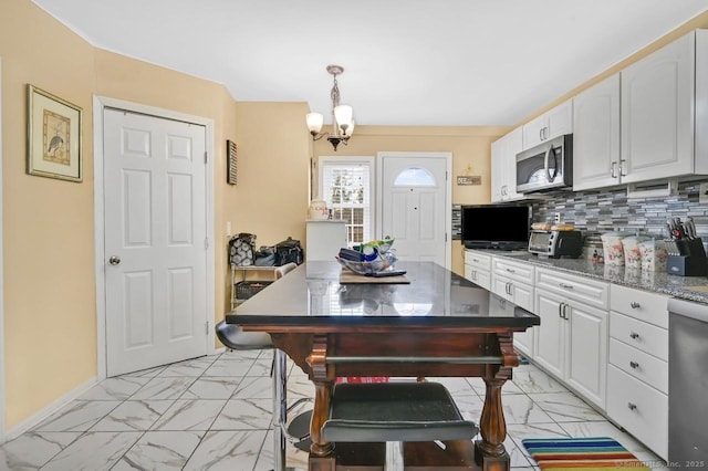 809 Burnside Ave, East Hartford, CT 06108 - kitchen with appliances with stainless steel finishes, light marble finish floors, white cabinets, a chandelier, and backsplash