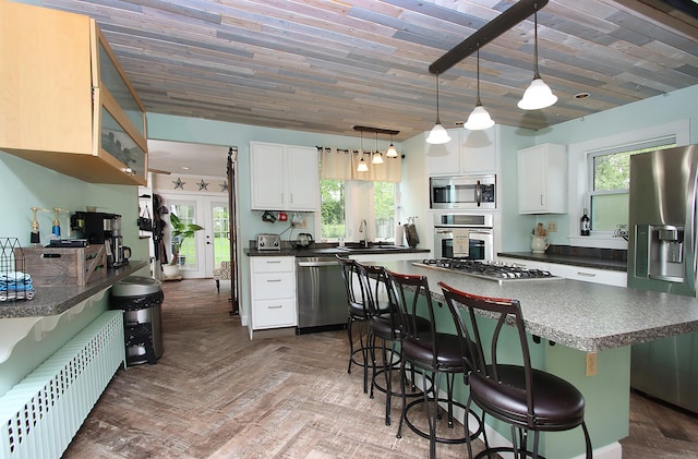 156 Clinton Hill Rd, Wolcott, CT 06716 - kitchen featuring appliances with stainless steel finishes, radiator heating unit, dark countertops, and a breakfast bar area