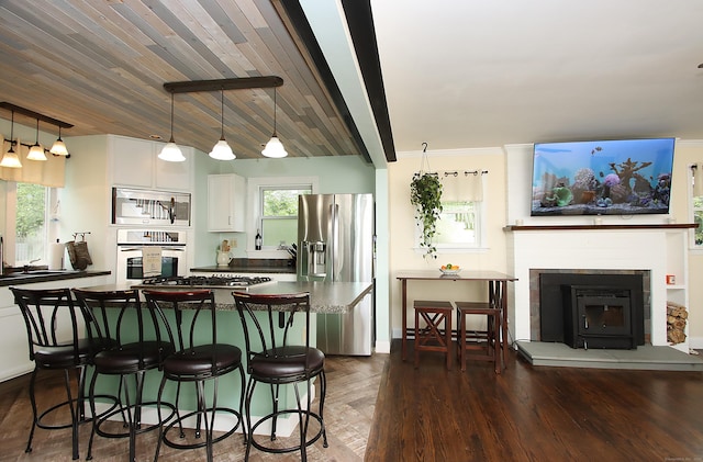 156 Clinton Hill Rd, Wolcott, CT 06716 - kitchen featuring appliances with stainless steel finishes, a fireplace with raised hearth, a kitchen bar, and dark countertops