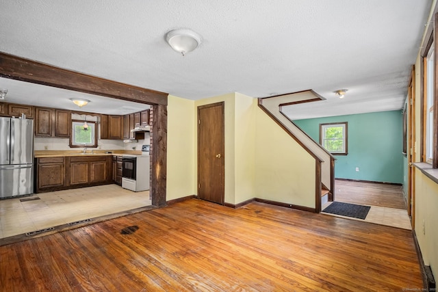 33 Hurlbut Rd, Tolland, CT 06084 - kitchen with freestanding refrigerator, electric range, a sink, light wood-type flooring, and under cabinet range hood