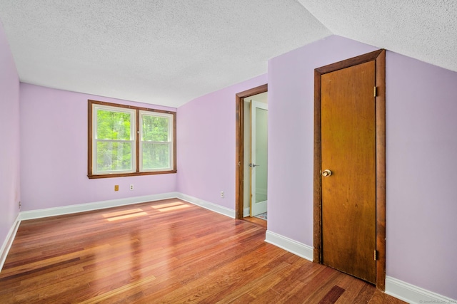 33 Hurlbut Rd, Tolland, CT 06084 - spare room with a textured ceiling, wood finished floors, lofted ceiling, and baseboards