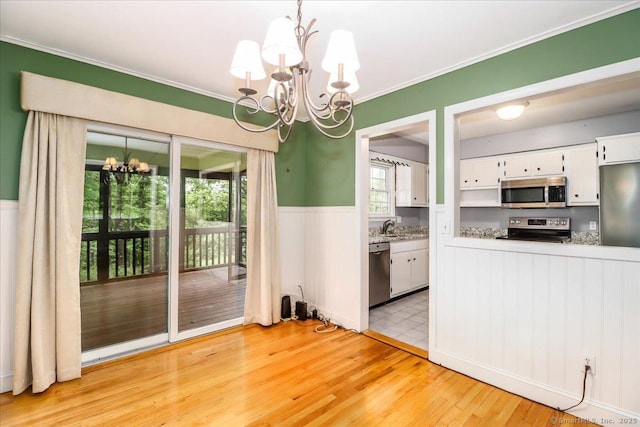 31 Buckingham Rd, New Milford, CT 06776 - unfurnished dining area with a chandelier, wainscoting, light wood-style flooring, a sink, and ornamental molding