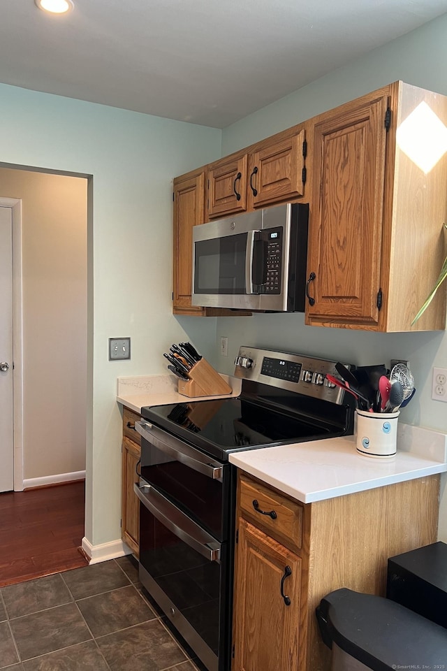 123 Old Belden Hill Rd Apt 5, Norwalk, CT 06850 - kitchen featuring appliances with stainless steel finishes, light countertops, brown cabinets, dark tile patterned floors, and baseboards