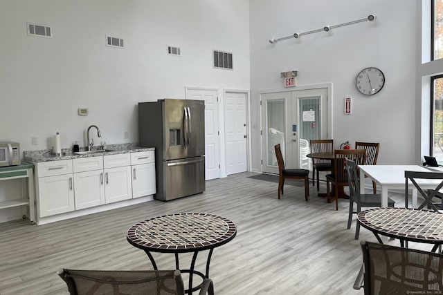 123 Old Belden Hill Rd Apt 5, Norwalk, CT 06850 - kitchen featuring stainless steel appliances, a high ceiling, light wood-style flooring, light stone counters, and white cabinets