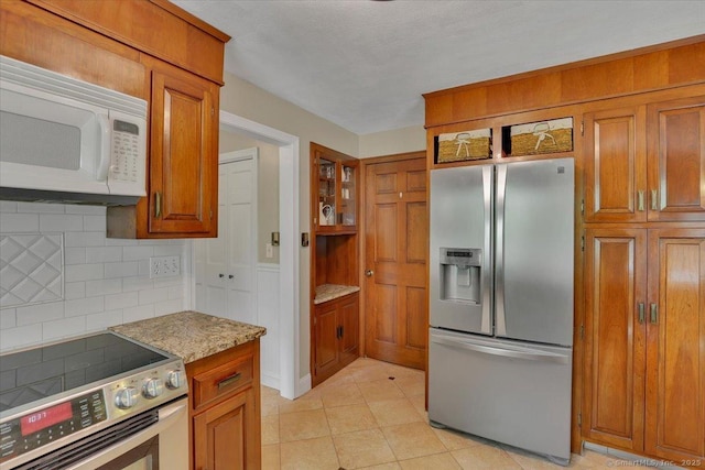 190 Bronson Dr, Middlebury, CT 06762 - kitchen featuring appliances with stainless steel finishes, brown cabinets, decorative backsplash, and light tile patterned flooring
