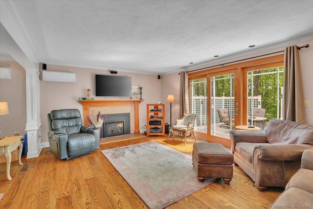 190 Bronson Dr, Middlebury, CT 06762 - living area featuring crown molding, a wall mounted AC, ornate columns, wood finished floors, and a fireplace with flush hearth