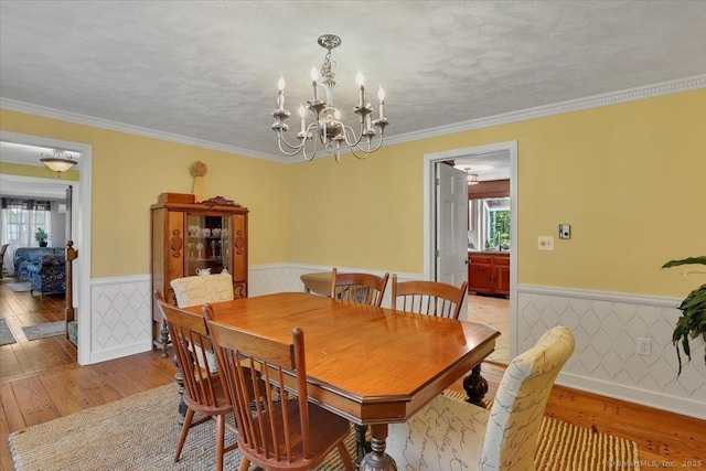 190 Bronson Dr, Middlebury, CT 06762 - dining space featuring a wainscoted wall, light wood-style floors, a chandelier, ornamental molding, and a textured ceiling