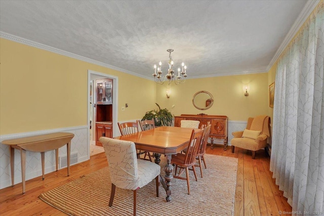 190 Bronson Dr, Middlebury, CT 06762 - dining area with light wood-type flooring, a chandelier, wainscoting, and crown molding