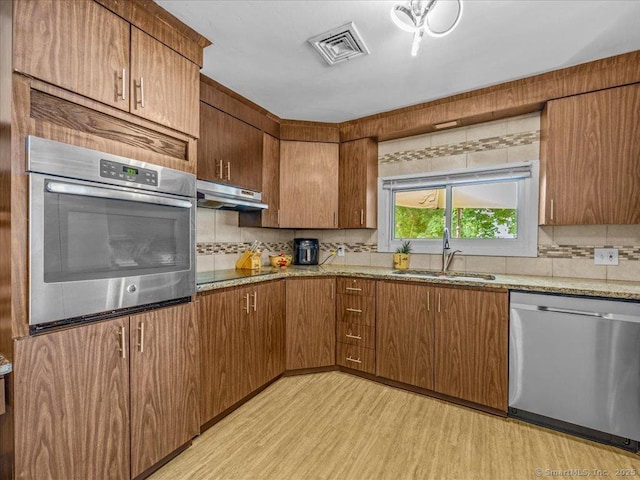 18 Geer Ave, Norwich, CT 06360 - kitchen featuring appliances with stainless steel finishes, a sink, under cabinet range hood, tasteful backsplash, and light wood-style flooring