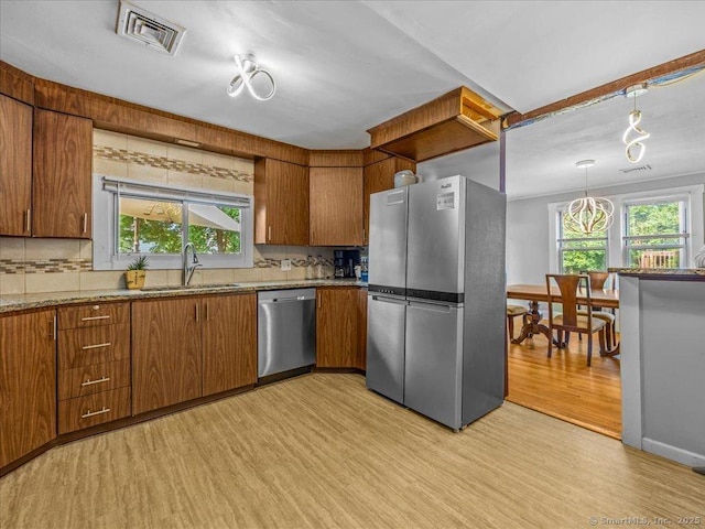 18 Geer Ave, Norwich, CT 06360 - kitchen with stainless steel appliances, a sink, light wood-style floors, tasteful backsplash, and brown cabinetry