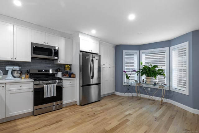 21 Summer Brook Way, Seymour, CT 06483 - kitchen with stainless steel appliances, baseboards, light wood finished floors, light countertops, and decorative backsplash