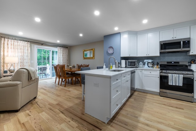 21 Summer Brook Way, Seymour, CT 06483 - kitchen featuring appliances with stainless steel finishes, a sink, a peninsula, light wood-style flooring, and backsplash