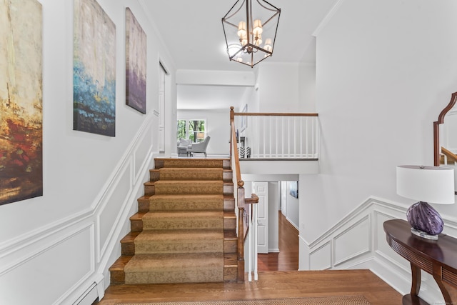 53 Pinnacle Rock Rd, Stamford, CT 06903 - stairs featuring a decorative wall, wood finished floors, wainscoting, a chandelier, and a baseboard radiator
