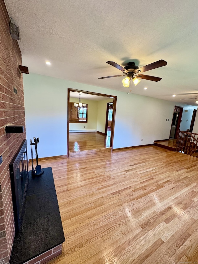 588 Poquonock Ave, Windsor, CT 06095 - unfurnished living room featuring ceiling fan, light wood finished floors, a brick fireplace, a textured ceiling, and baseboards