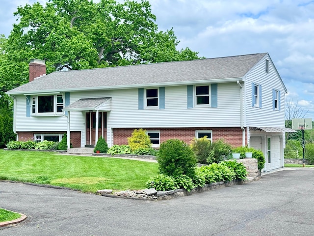 588 Poquonock Ave, Windsor, CT 06095 - split foyer home with a chimney, an attached garage, a front lawn, asphalt driveway, and brick siding